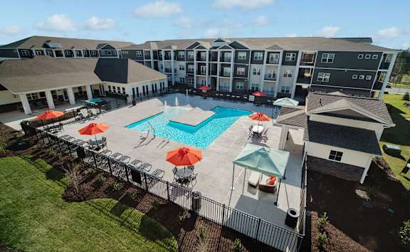 A large building with a pool and umbrellas.