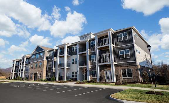 A large apartment complex with a parking lot in front.