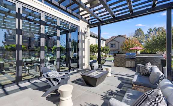 A modern outdoor patio with a glass wall and a stone fireplace.