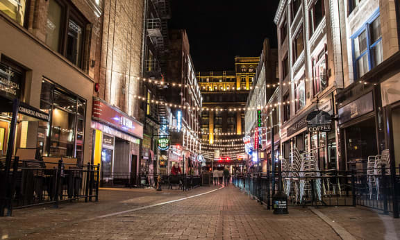 a city street at night with people walking down it