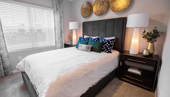 A bedroom with a large bed and a nightstand with a lamp.