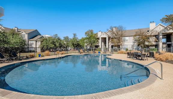 A large swimming pool with lounge chairs and a building in the background.