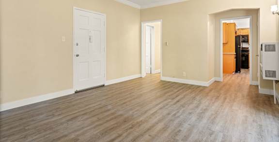 A room with a white door and a brown floor.