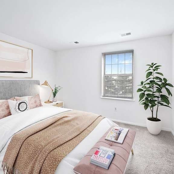 A bedroom with a large bed, a potted plant, and a window.