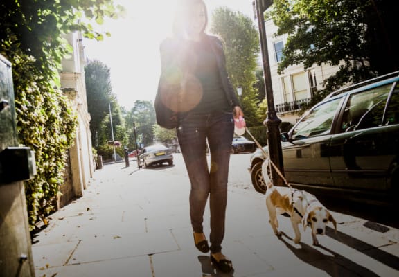 a woman walking her dog down a sidewalk