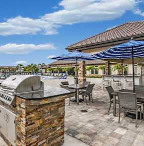 a barbecue grill on a patio with a lawn and apartments in the background