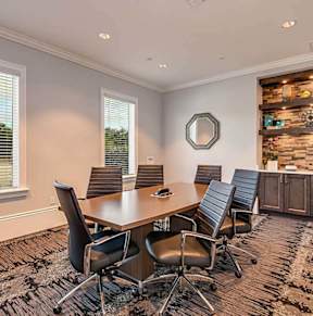 a conference room with a desk and chairs and a mirror