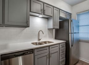 kitchen with gray cabinets and a stainless steel refrigerator at THE EASTWOOD, AUSTIN, TX