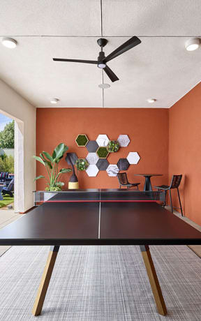 a ping pong table in a living room with an orange wall at Citron Apartment Homes, California, 92506