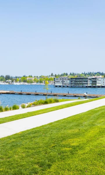 a sidewalk leading down to a body of water with buildings in the background at Cogir of Kirkand in Kirkand, WA