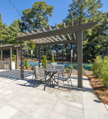 a patio with a pergola and a pool in the background at Elme Cumberland Apartments, Smyrna, GA, 30080