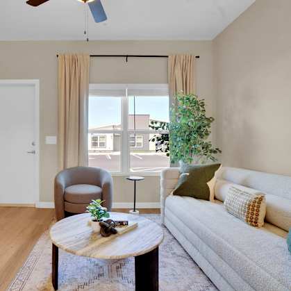 A living room with a grey couch, a wooden coffee table, and a painting on the wall.