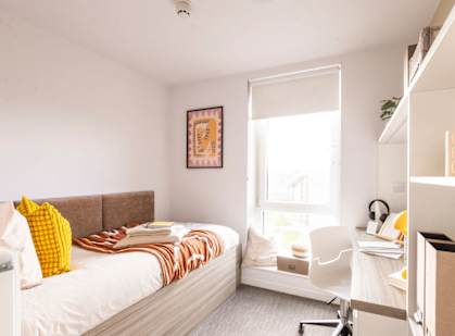 a bedroom with a bed and a desk and a window