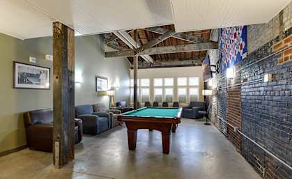 A room with a pool table and leather chairs.