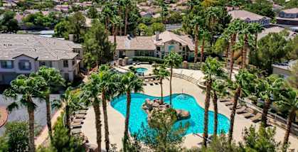an aerial view of a swimming pool with palm trees and houses