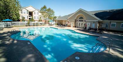 A large swimming pool in front of a building with a sunny day.