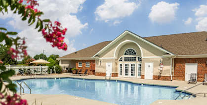 A pool in front of a house with a brown roof.