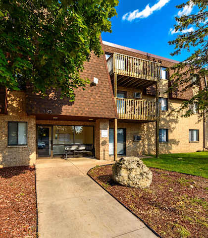 A large rock sits in the middle of a grassy area in front of a building.