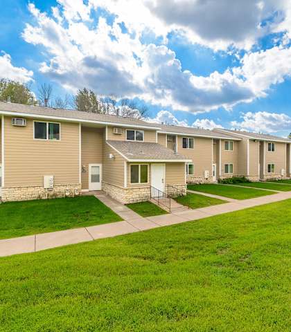 A row of houses with green lawns in front.