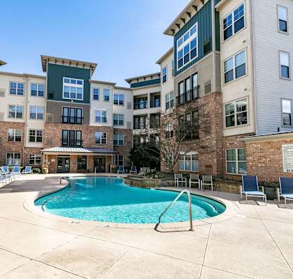 a swimming pool with chaise lounge chairs and an apartment building in the background
