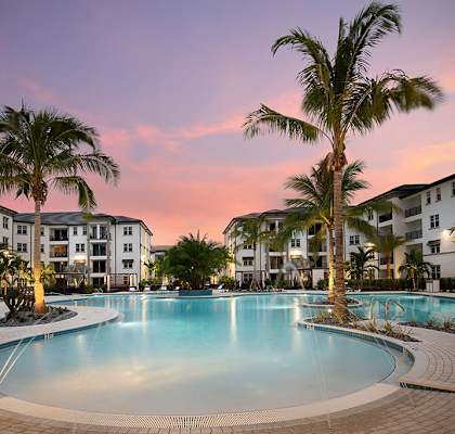 a large swimming pool with palm trees at sunset at Inspira, Florida