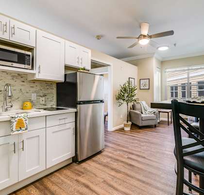 A kitchen with white cabinets and a black chair.