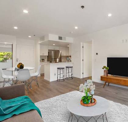 a living room with a television and a kitchen in the background