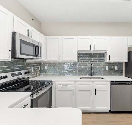 A kitchen with white cabinets and appliances.
