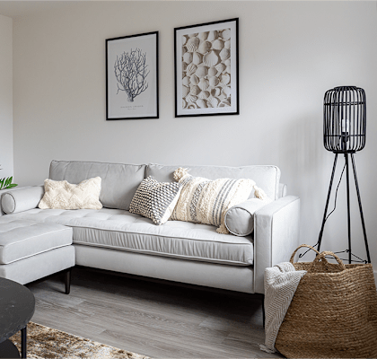 A living room with a white couch, a black table, and two framed pictures on the wall.