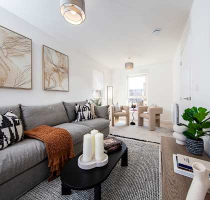 A living room with a grey couch and a large mirror on the wall.