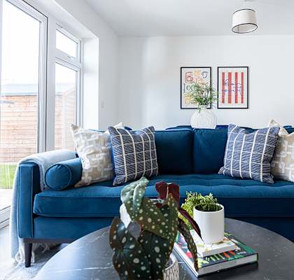 A blue couch with pillows and a vase on a coffee table in a room.