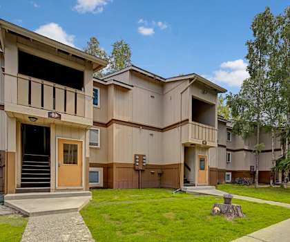 The stunning pathways surrounded by grass and trees leading to the entrances to the tan and brown apartment buildings at the Greenbriar Apartment Homes