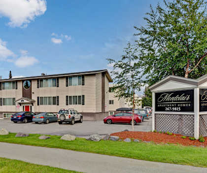 The exterior sign, building, and parking lot with trees and greenery of Montclair Apartment Homes. 