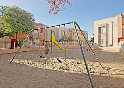 a playground with a swing set in front of a building