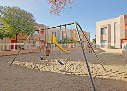 a playground with a swing set in front of a building