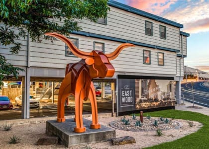 a large orange sculpture of a cow in front of a building at THE EASTWOOD, AUSTIN