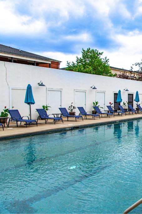 A pool with blue umbrellas and chairs at French District Villas Apartments, St. Charles, MO 63301