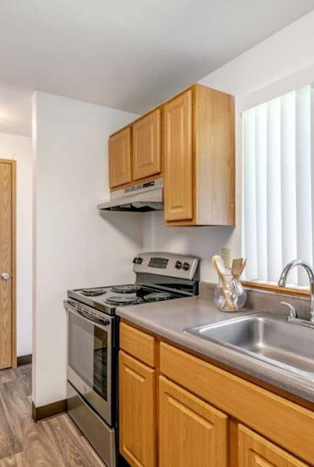 A kitchen with wooden cabinets and a stainless steel sink.at Alder Creek Apartments, Vancouver