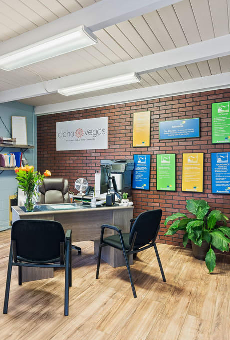 a room with a desk and chairs with a brick wall in the background