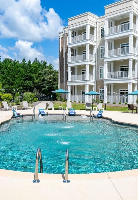 a large pool in front of a building with umbrellas at The Station at River Crossing, Macon, 31210