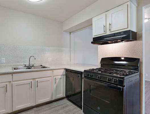 A kitchen with a black stove and white cabinets.