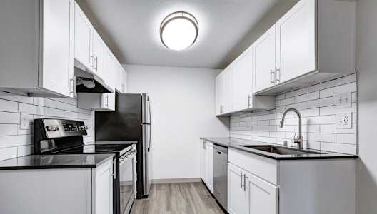 a kitchen with white cabinets and black counter tops