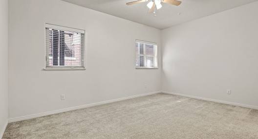 an empty living room with a ceiling fan and a window