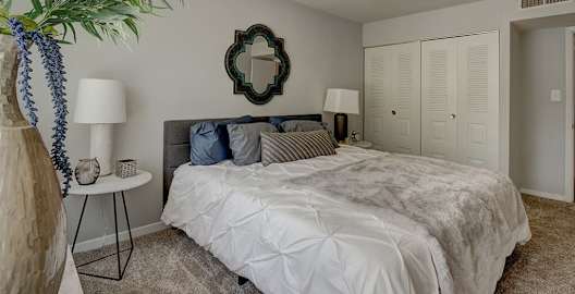 A bedroom with a large bed and a mirror on the wall at Oaks at Oxon Hill, Oxon Hill, Maryland