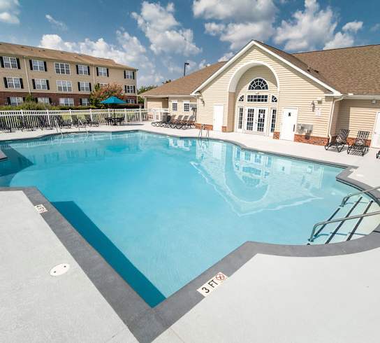 A large outdoor swimming pool with a diving board and lounge chairs.
