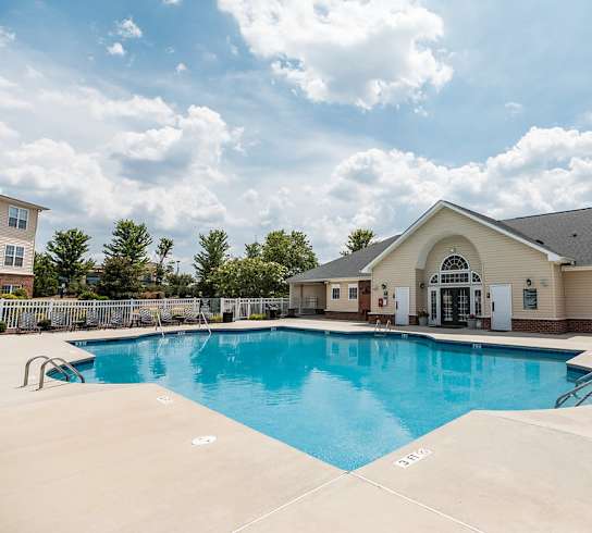 A large swimming pool in front of a building with a white exterior.