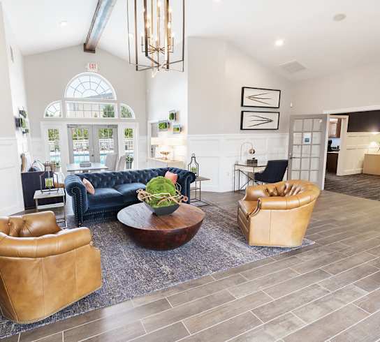 A living room with a blue couch, a brown leather chair, and a brown leather ottoman.