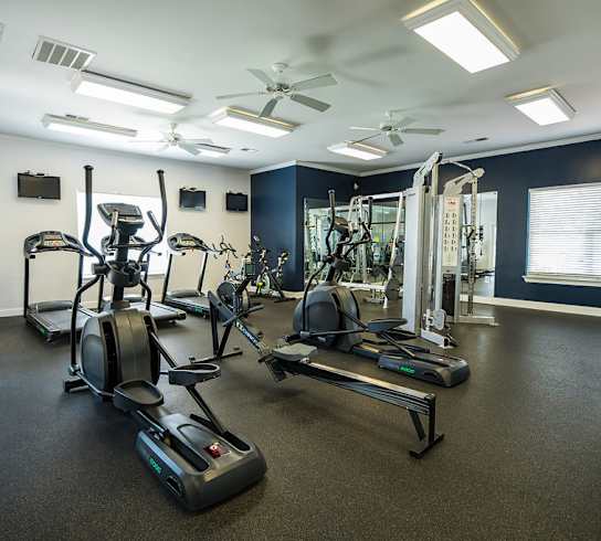 A spacious gym with a variety of equipment including treadmills, elliptical machines, and a weight bench.