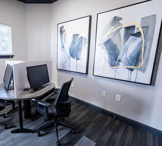 A room with a table, chairs and two computers.