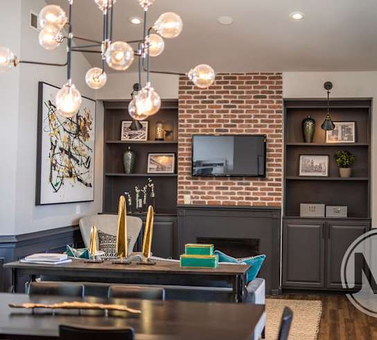 A modern dining room with a brick wall and a wooden table.
